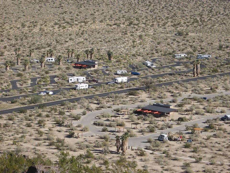 Aerial view of a desert campground with RVs among scattered palms