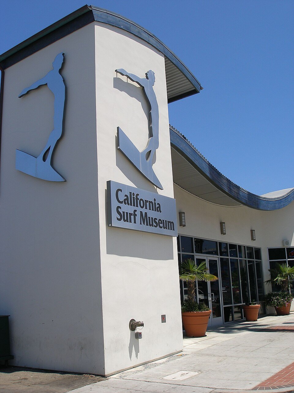 The California Surf Museum building with a surfer sculpture and the museum sign