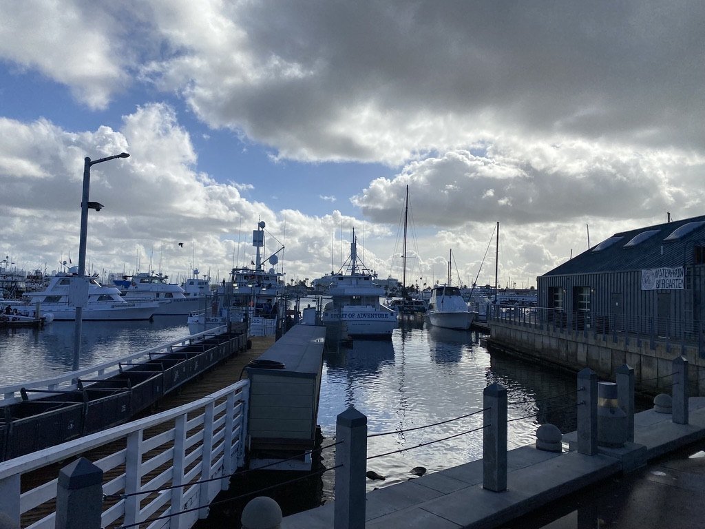 Dock, railings and moored boats under big clouds