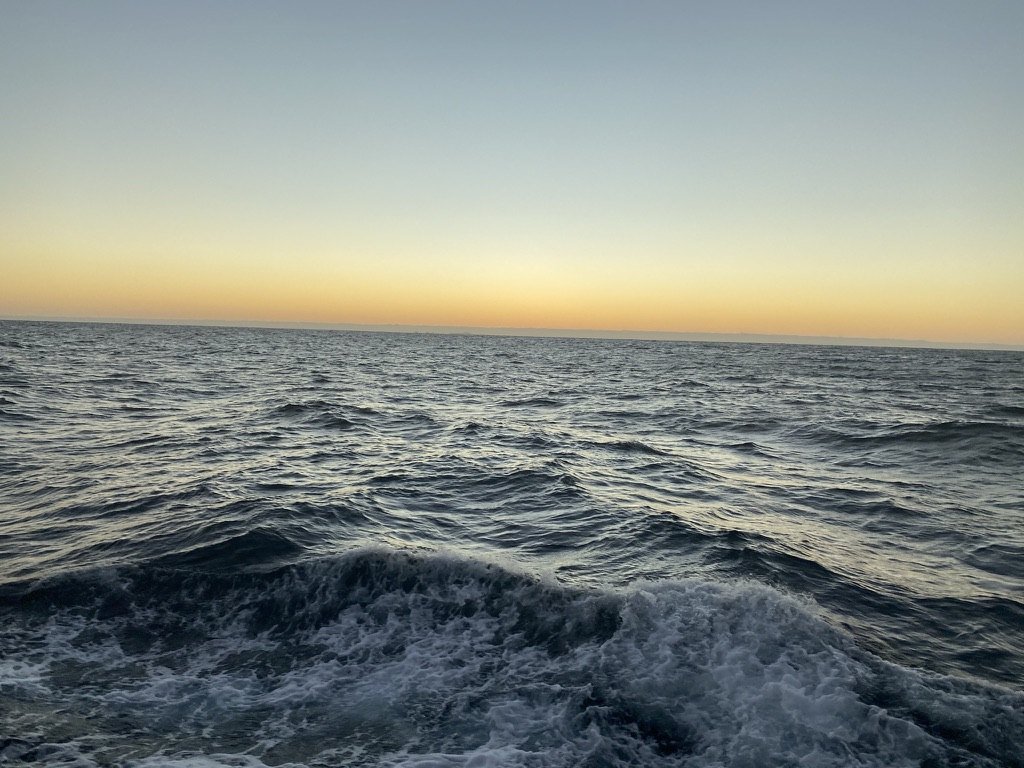 Foamy swell under a glowing orange horizon