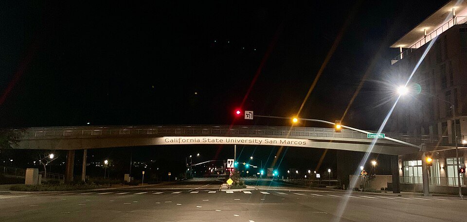 A pedestrian bridge at night with the words California State University San Marcos