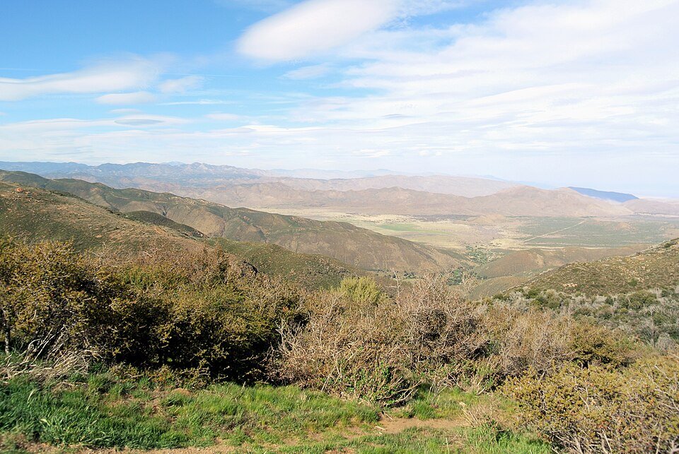 A long view east from the Laguna Mountains over green slopes toward the desert