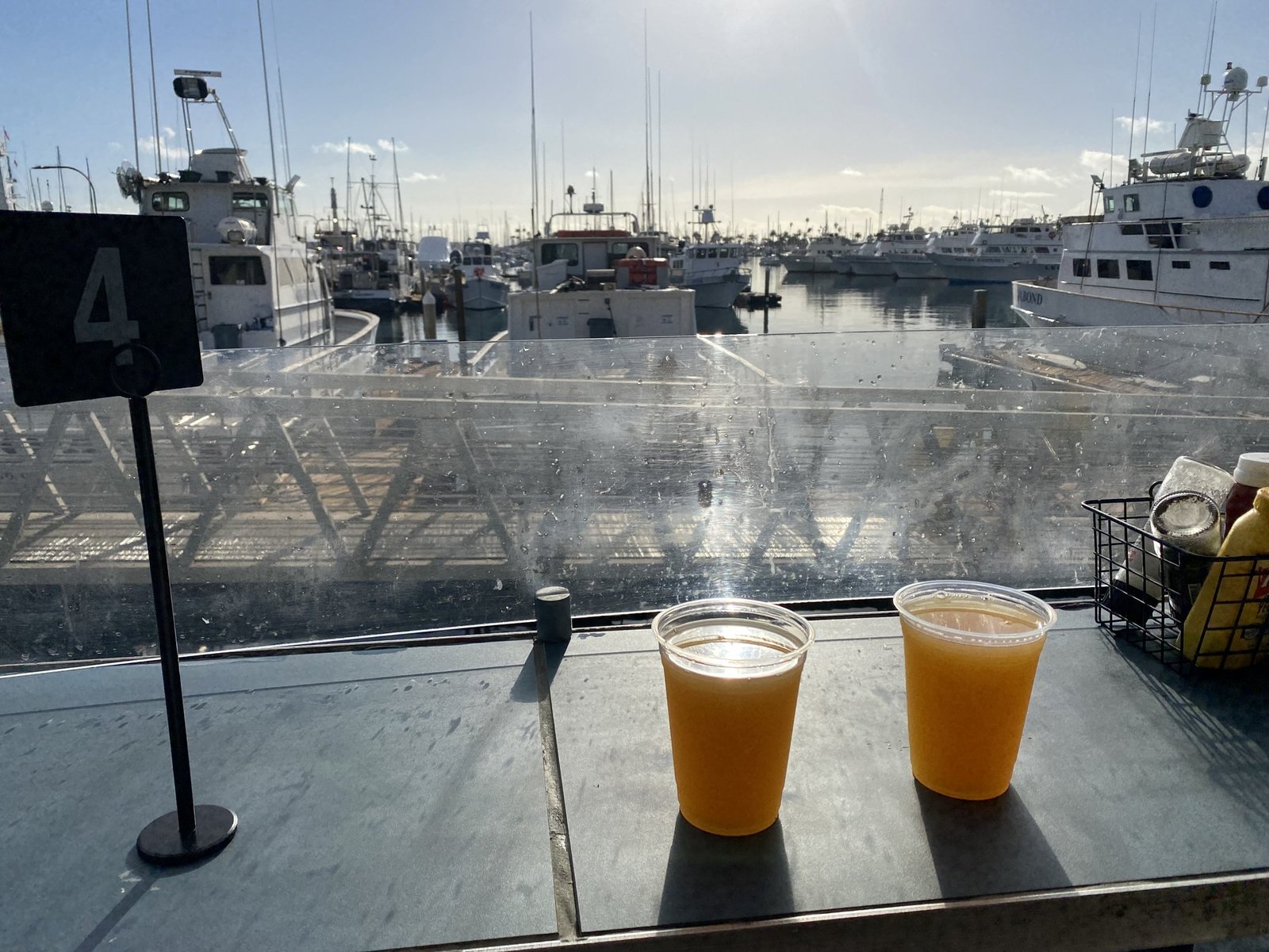 Two cups of orange juice on a table on the patio at Mitch's Seafood, with the sportfishing boats at their slips beyond the glass