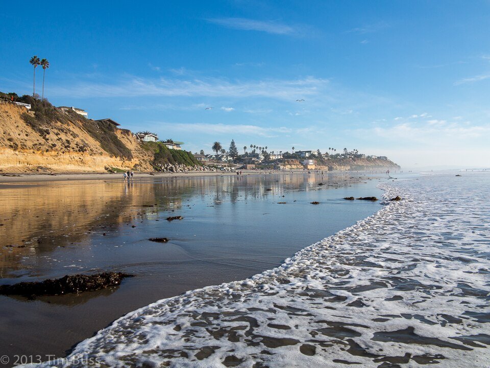 Waves washing onto the sand at Moonlight Beach in Encinitas with bluffs in the distance