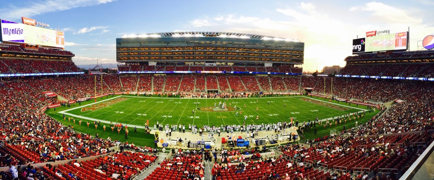A football stadium full of fans watching a game in daylight