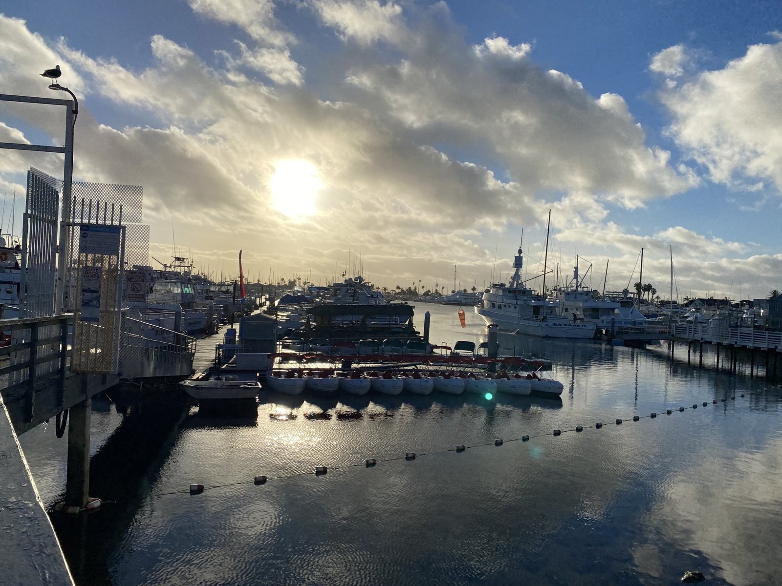Sunset over the sportfishing harbor at Point Loma, with boats at their slips under a cloudy sky
