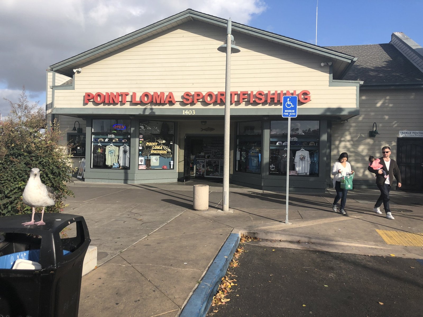 The Point Loma Sportfishing building, with its red sign above the entrance and a seagull on a trash can in front
