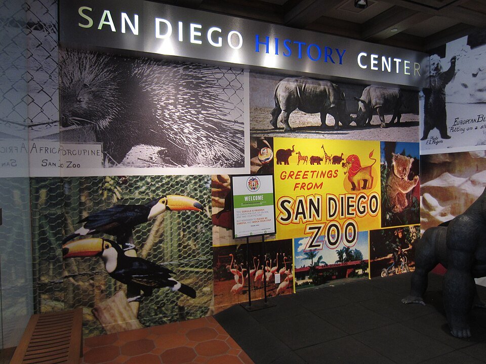 Exhibit wall with a San Diego History Center sign, vintage Zoo posters and a toucan picture