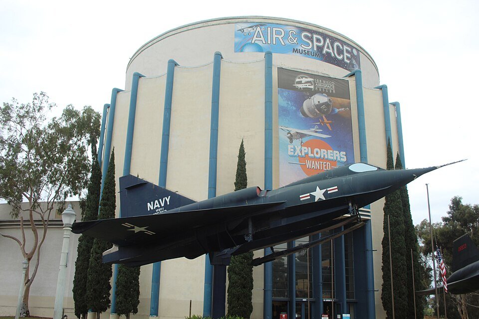 The round San Diego Air and Space Museum building with a Navy jet on display in front