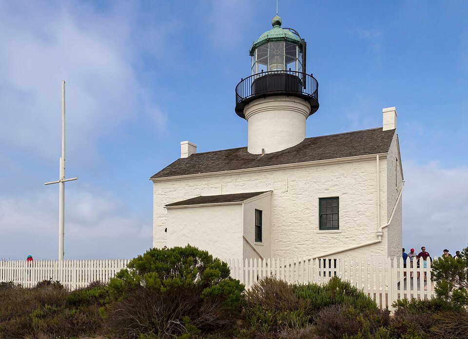 The Old Point Loma Lighthouse, a white building with a short tower, under a blue sky