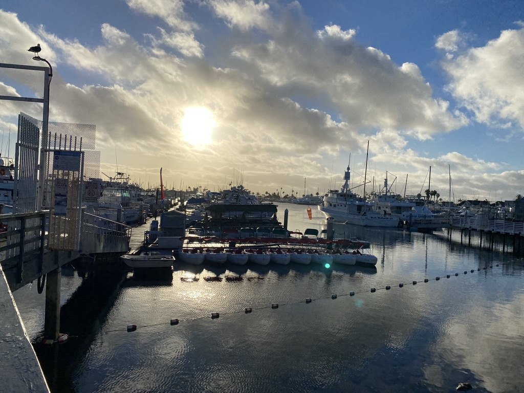 Sun breaking through clouds over a marina with reflections on the water