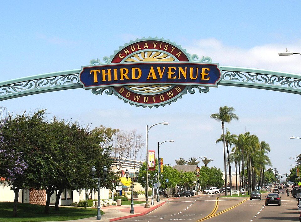 The Third Avenue arch over the street in Downtown Chula Vista, with palm trees and shops beyond