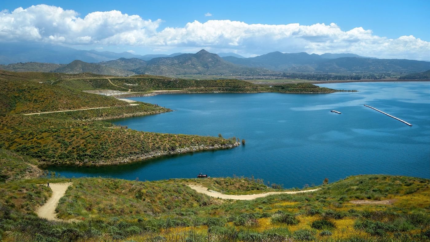 A calm lake with green hills and mountains beyond